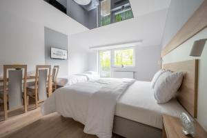 a white bedroom with a bed and a dining room at Błękitna Fala Resort in Dąbki +10 photos