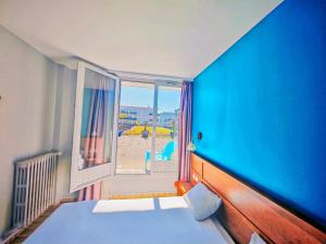 a bedroom with a blue wall and a bed and a window at ibis Styles Le Havre Centre in Le Havre