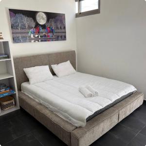 a bed with white sheets and pillows in a room at סויטת החורש in Shelomi +28 photos