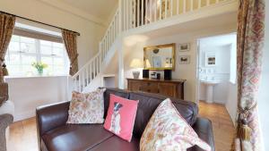 a living room with a brown leather couch with pillows at Pant Glas in Penmaen-mawr