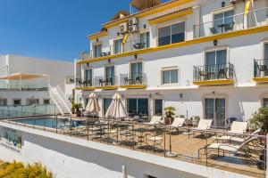 a hotel with a balcony with chairs and a swimming pool at Vila Sao Vicente Boutique (Adults Only) in Albufeira