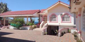 a pink and white house with a driveway at Amerie Rae Resort in Bangui