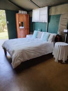 a bedroom with a large bed and a table at Sabie River Camp in Sabie