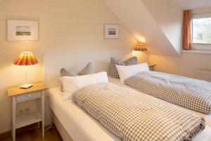 a bedroom with two beds and a table with lamps at Freesenhoff - Ofdak in Langeoog