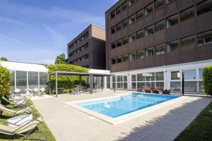 a swimming pool in front of a building at Best Western Plus Hotel Farnese in Parma