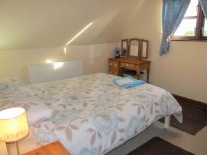 a bedroom with a bed with a floral comforter at Maytree Cottage in East Dereham