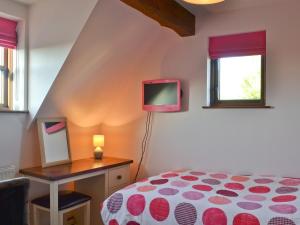 a bedroom with a bed and a tv on a table at Maytree Cottage in East Dereham +9 photos