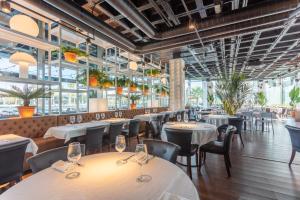 a restaurant with white tables and chairs and windows at aparto Diagonal Suites in Esplugues de Llobregat