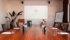 a large conference room with a long table in front of a screen at Genuss Am Hof in Halbturn