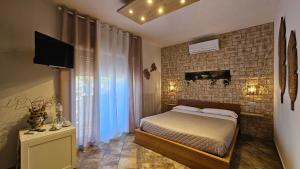 a bedroom with a bed and a brick wall at B&B Triskèles in Giardini Naxos