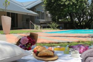 a picnic blanket with food and flowers next to a pool at Luxury Heights Bed and Breakfast in Newcastle