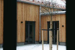 a tree in front of a building with two doors at Grünbauer - Der Landgasthof in Reuth bei Erbendorf