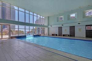 a large swimming pool in a building with windows at Panoramic Lakeview Resort Living 3BDR with Gym, Pool, Free parking in Toronto