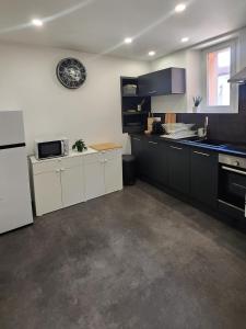 a kitchen with black and white cabinets and a microwave at Charmant logement hyper centre in Sélestat