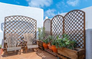 a patio with three chairs and potted plants at La terraza de Albatros in La Isleta del Moro