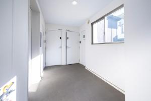 an empty hallway with white walls and a window at BK Residence Kawasaki in Kawasaki