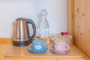 a tea kettle and two cups and a bottle on a table at Tourist farm Mulej in Bled