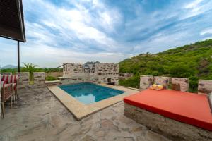 a pool on a patio with a table and chairs at Maya Luxury The Quila Udaipur in Udaipur