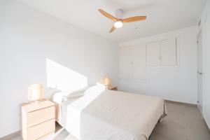 a white bedroom with a bed and a ceiling fan at Casa Ingravita - Oceanfront Tranquility in Cunit