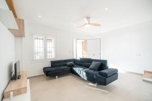 a living room with a black couch and a ceiling fan at Casa Ingravita - Oceanfront Tranquility in Cunit