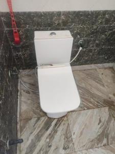 a white toilet in a bathroom with a red hose at Shri Ved Vrinda Dham Aashram in Chhatikara