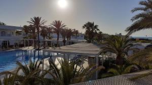 Blick auf einen Swimmingpool mit Palmen und Gebäuden in der Unterkunft Riad Meninx in Bin Rhilouf