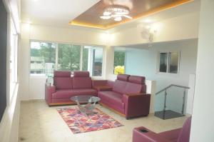 a living room with purple couches and a glass table at Yercaud Rathna Residency in Yercaud
