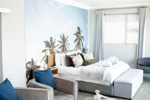 a bedroom with a bed and a chair and a window at Bay Lodge on the Beach in Mossel Bay +50 photos