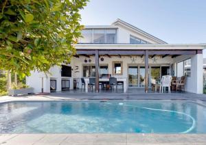 a house with a swimming pool in front of a house at Corner Delight at Onrust Beach in Hermanus