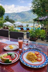 a table with plates of food and drinks on it at Zoé’s Paradise Waterfront Hotel in Tuktuk Siadong