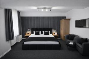 a bedroom with a large bed and two chairs at Arena Hotel in Gelsenkirchen