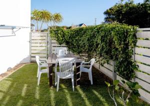 a table and chairs on a lawn with a fence at Corner Delight at Onrust Beach in Hermanus