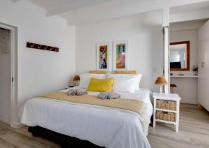 a bedroom with a large white bed with yellow pillows at Corner Delight at Onrust Beach in Hermanus +29 photos