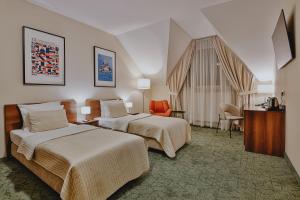 ein Hotelzimmer mit zwei Betten und einem orangefarbenen Stuhl in der Unterkunft Hotel Kantoria in Tarnów + 53 Fotos