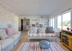 a living room with two white couches and a kitchen at Corner Delight at Onrust Beach in Hermanus