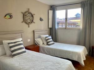 two beds in a room with a window at Casco antiguo en Ribadesella in Ribadesella