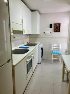 a kitchen with white cabinets and a sink and a dishwasher at Casco antiguo en Ribadesella in Ribadesella