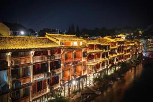 a row of buildings next to a river at night at 枫江月 in Fenghuang County