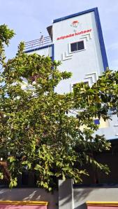 a white building with a tree in front of it at Sripadakuteer in Pithāpuram