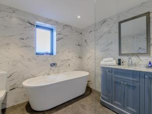 a bathroom with a tub and a sink and a mirror at 3 Bed in Belford oc-78057 in Ellington +28 photos