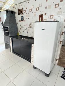 a white refrigerator in a kitchen with a counter at Casa centro de Peruíbe in Peruíbe