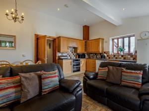 a living room with two leather couches and a kitchen at 3 Bed in Ellesmere oc-94419 in Dodleston