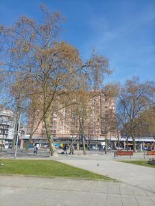 a park with trees and benches and a large building at Las Meanas Presbítero 6 in Avilés