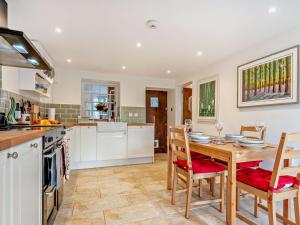 a kitchen with a wooden table and chairs and a kitchen with white cabinets at 2 Bed in Swindon oc-93489 in Bishopstone +16 photos