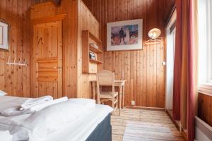 a bedroom with wooden walls and a bed and a table at Valen Cabins in Reine in Reine