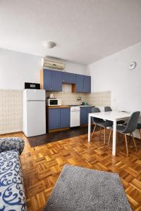 a kitchen with blue cabinets and a table and chairs at Orange city apartment's Repić in Biograd na Moru