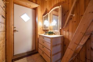 a bathroom with a sink and a mirror and a door at Valen Cabins in Reine in Reine +73 photos