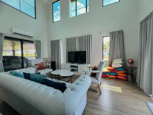 a living room with a couch and a tv at Gaia Pool Villa Khao Yai in Ban Bung Toei