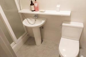a white bathroom with a toilet and a sink at Ara Guesthouse in Busan