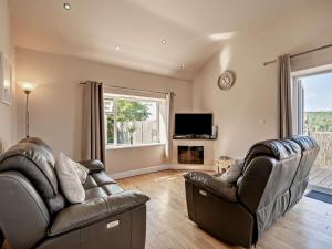 a living room with two leather chairs and a television at 2 Bed in Blakeney oc-54765 in Awre